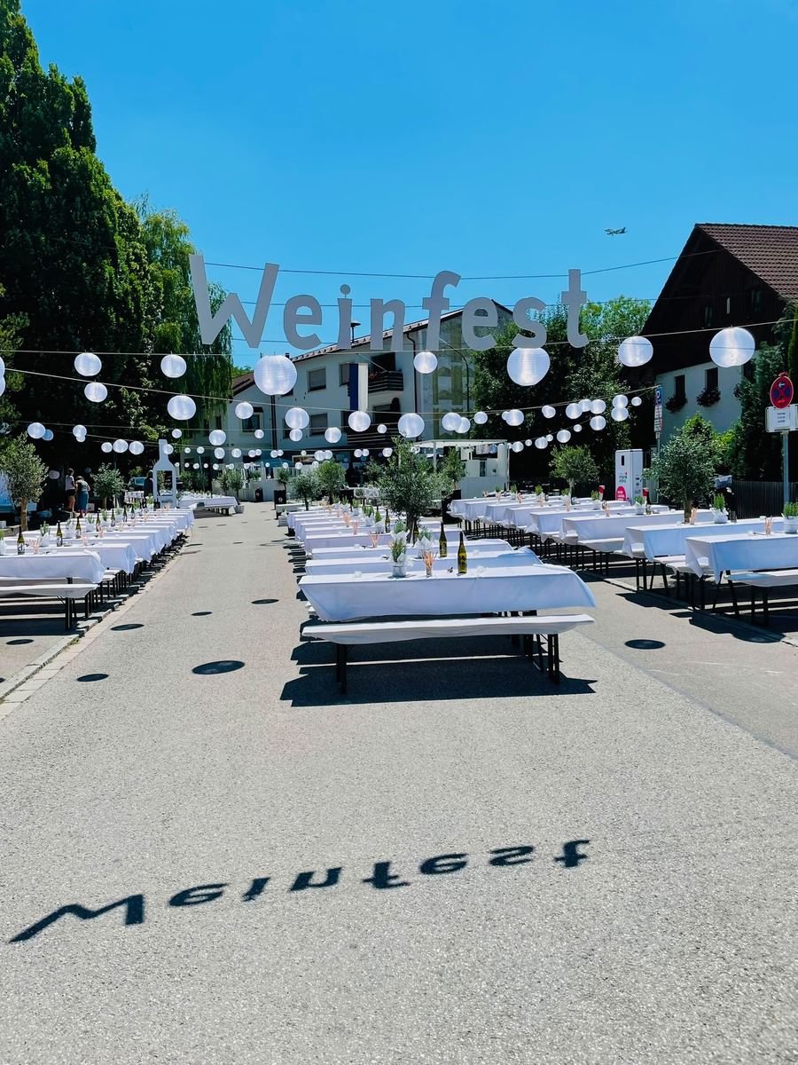 Festlich gedeckte Tische unter weißen Lampions und dem Weinfest-Schriftzug in Pulling